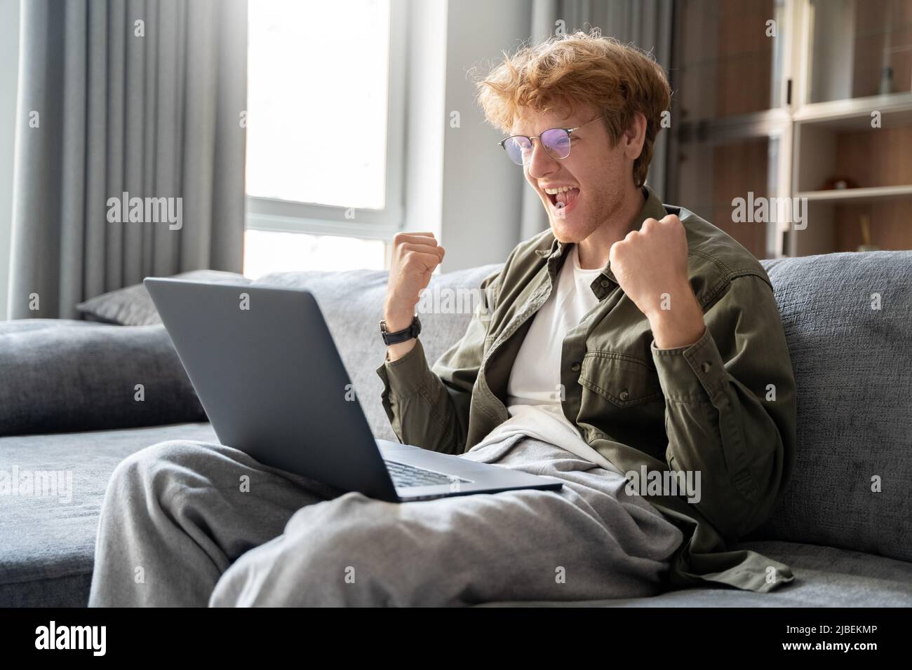 Excited young ginger man freelancer feeling winner having success at online work Stock Photo