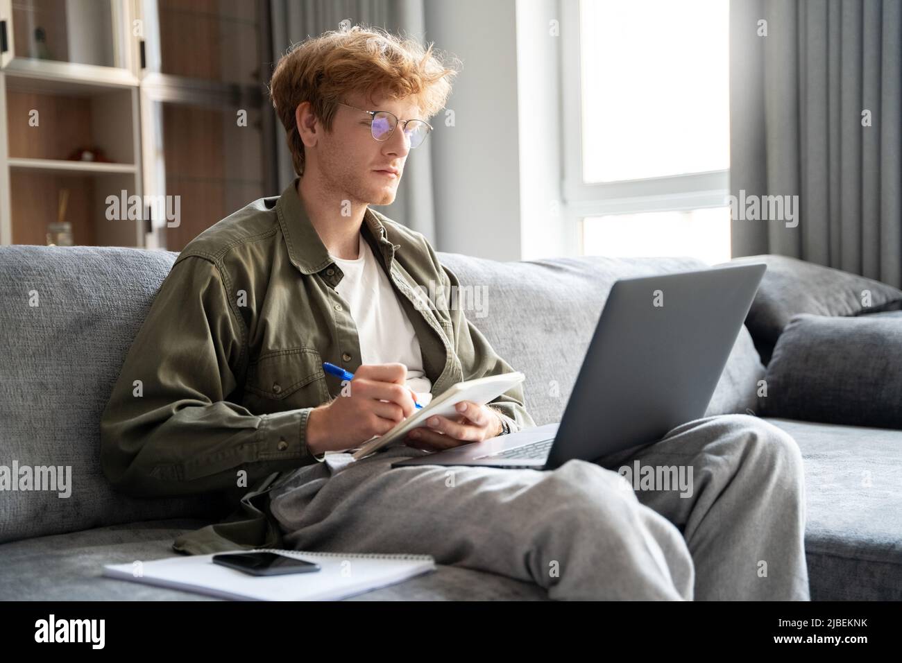 Young redhead business man manager looking at laptop watching online webinar Stock Photo