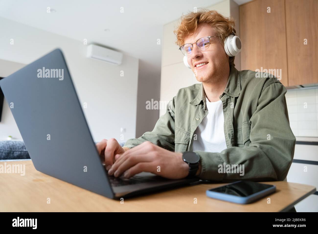 Young ginger man gamer playing video game, doing business videocall on laptop Stock Photo