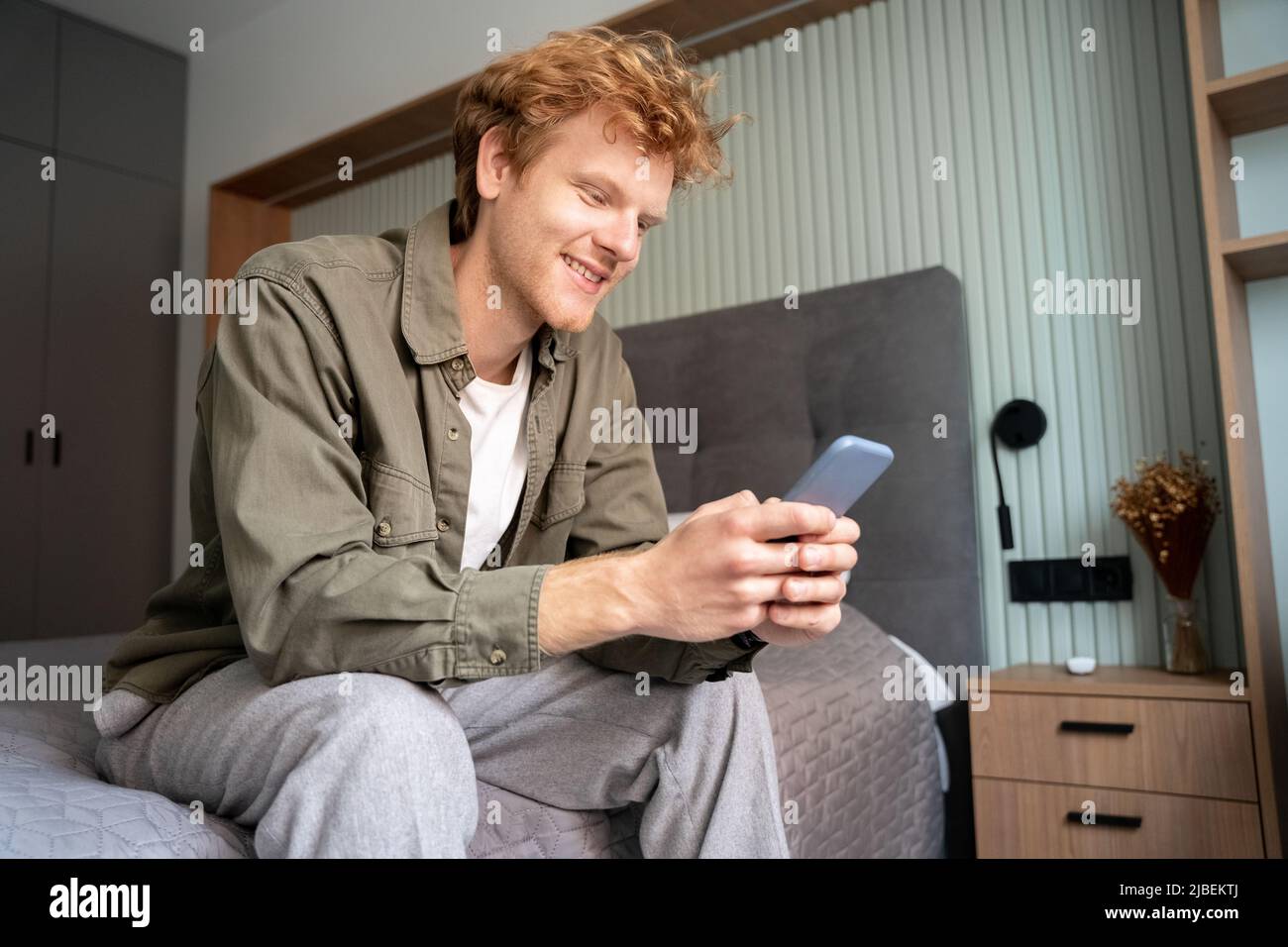 Smiling young adult ginger irish freelance business man using mobile phone Stock Photo
