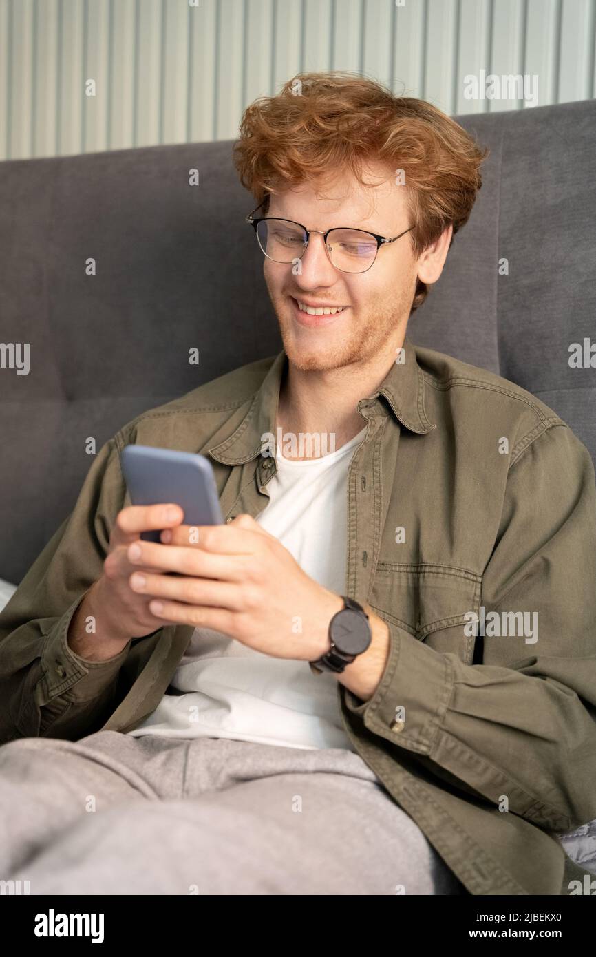 Smiling young ginger british man on virtual communication video call using phone Stock Photo