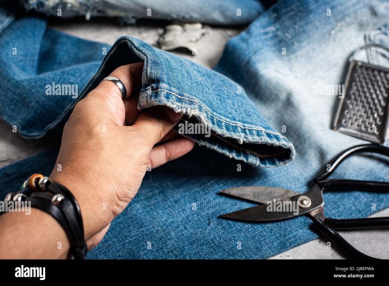 The man making ditressed jeans. DIY ripped jeans with scissors and