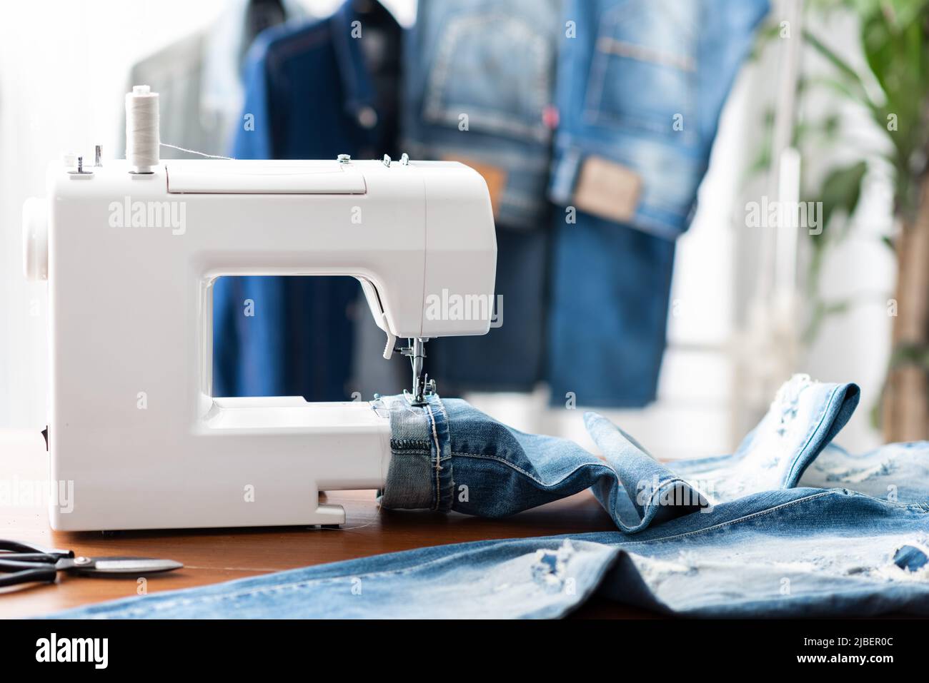 Tailor working with blue denim jeans. Tailor hem the blue jeans Stock