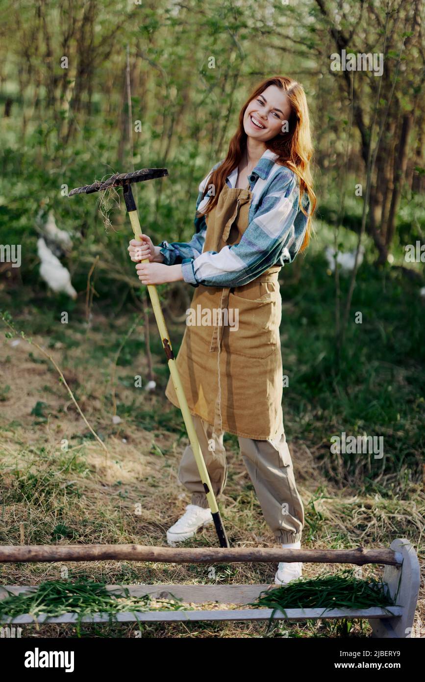 A woman farmer in work clothes and an apron works outdoors in nature