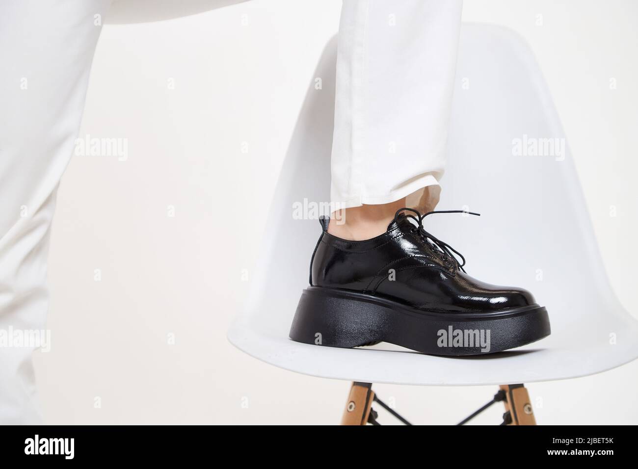Black female or male patent leather shoes on legs of woman. Shooting for catalog or an online store. A pair of shoes Stock Photo
