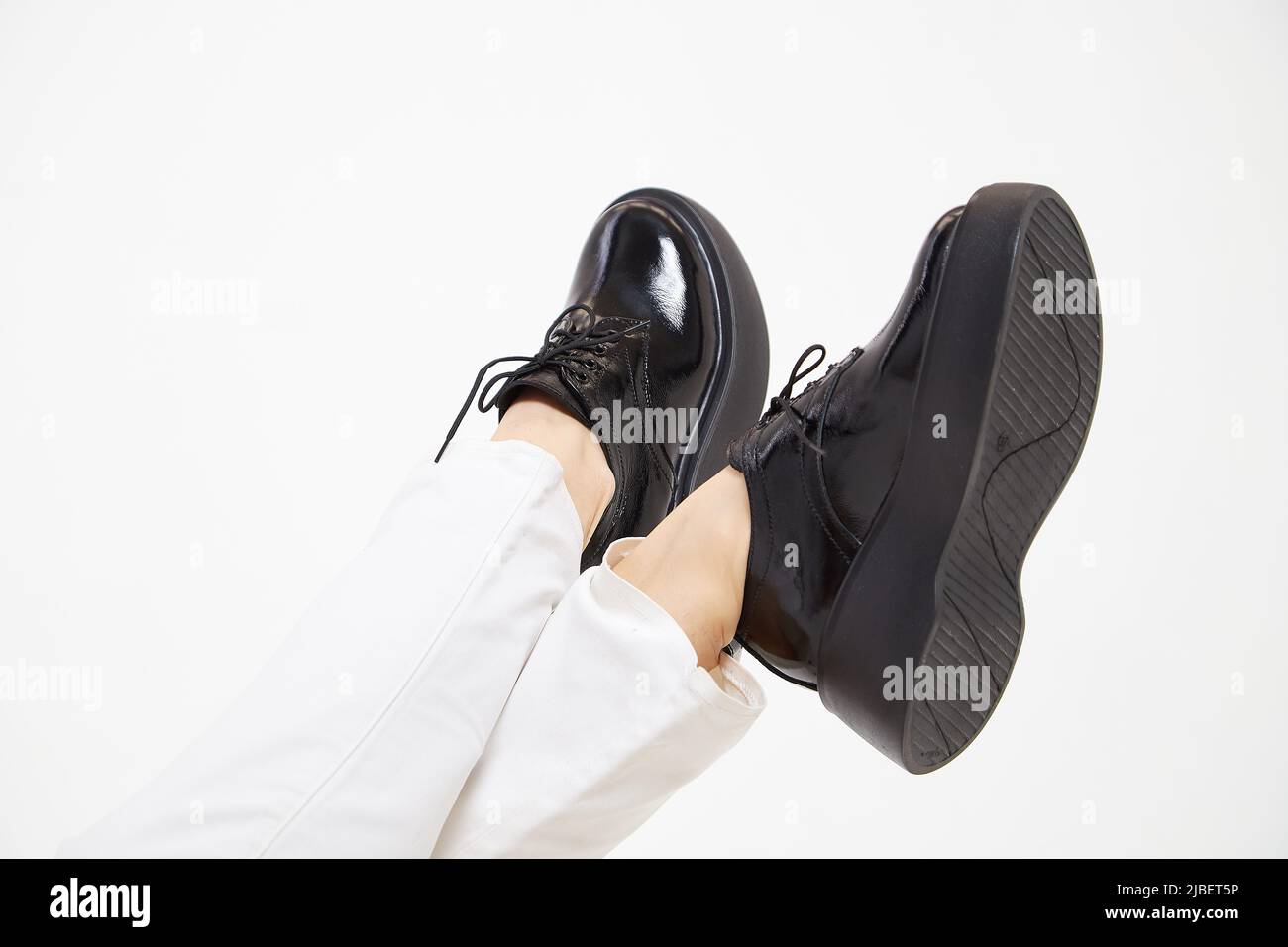 Black female or male patent leather shoes on legs of woman. Shooting for catalog or an online store. A pair of shoes Stock Photo