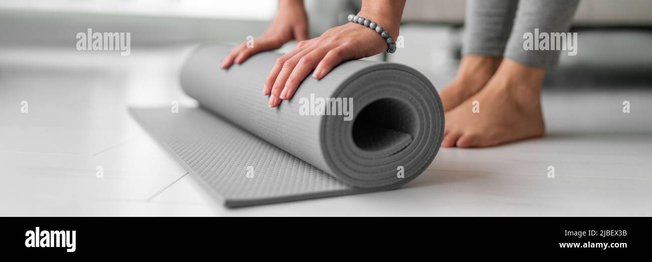 Yoga online class at home woman rolling mat on apartment floor for gym training or meditation banner panoramic. Feet and hands closeup Stock Photo