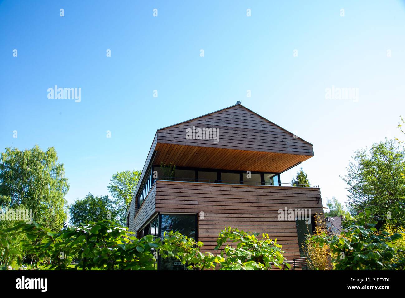 modern wooden house with blue sky, front view Stock Photo - Alamy