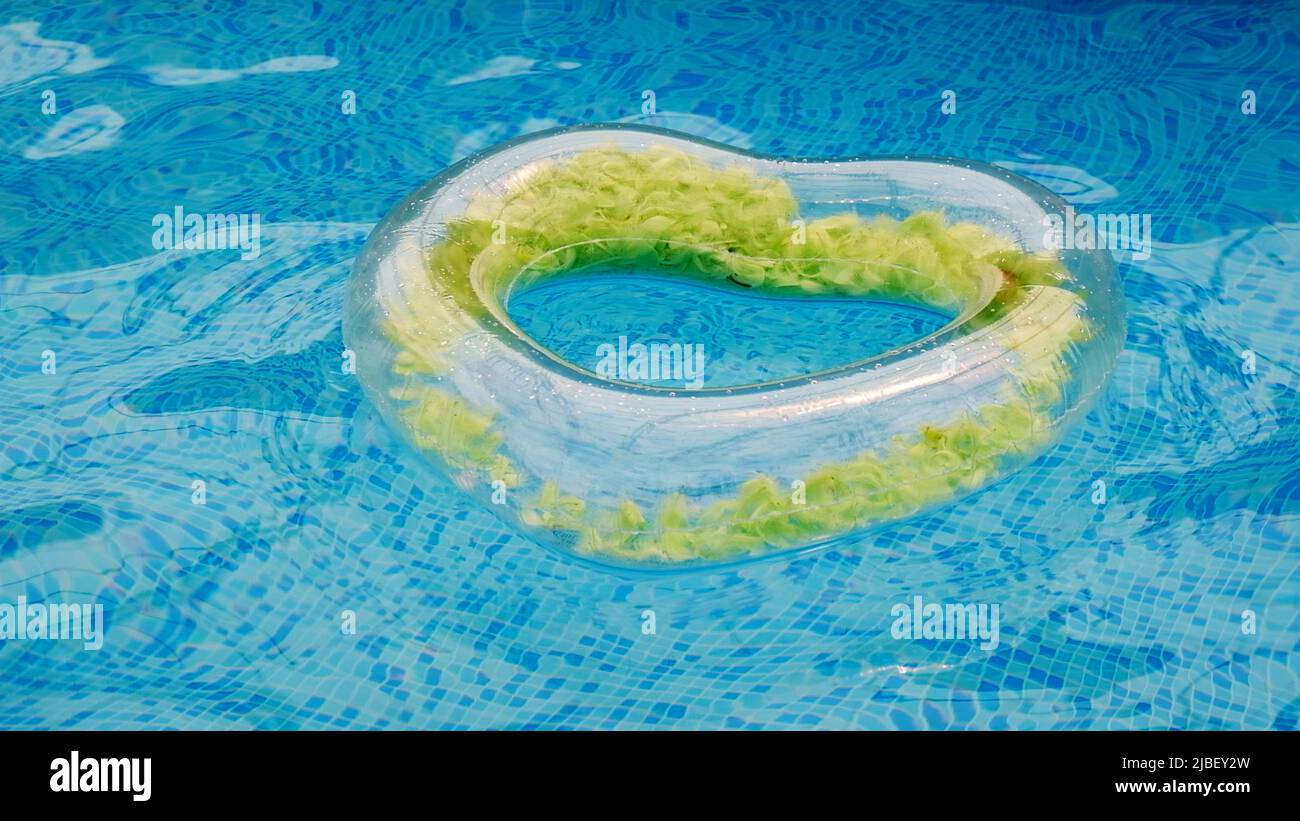 Floating rubber heart in water pool of crystal clean water surface. The concept of summer holidays, discounts, fun and summer.  Stock Photo