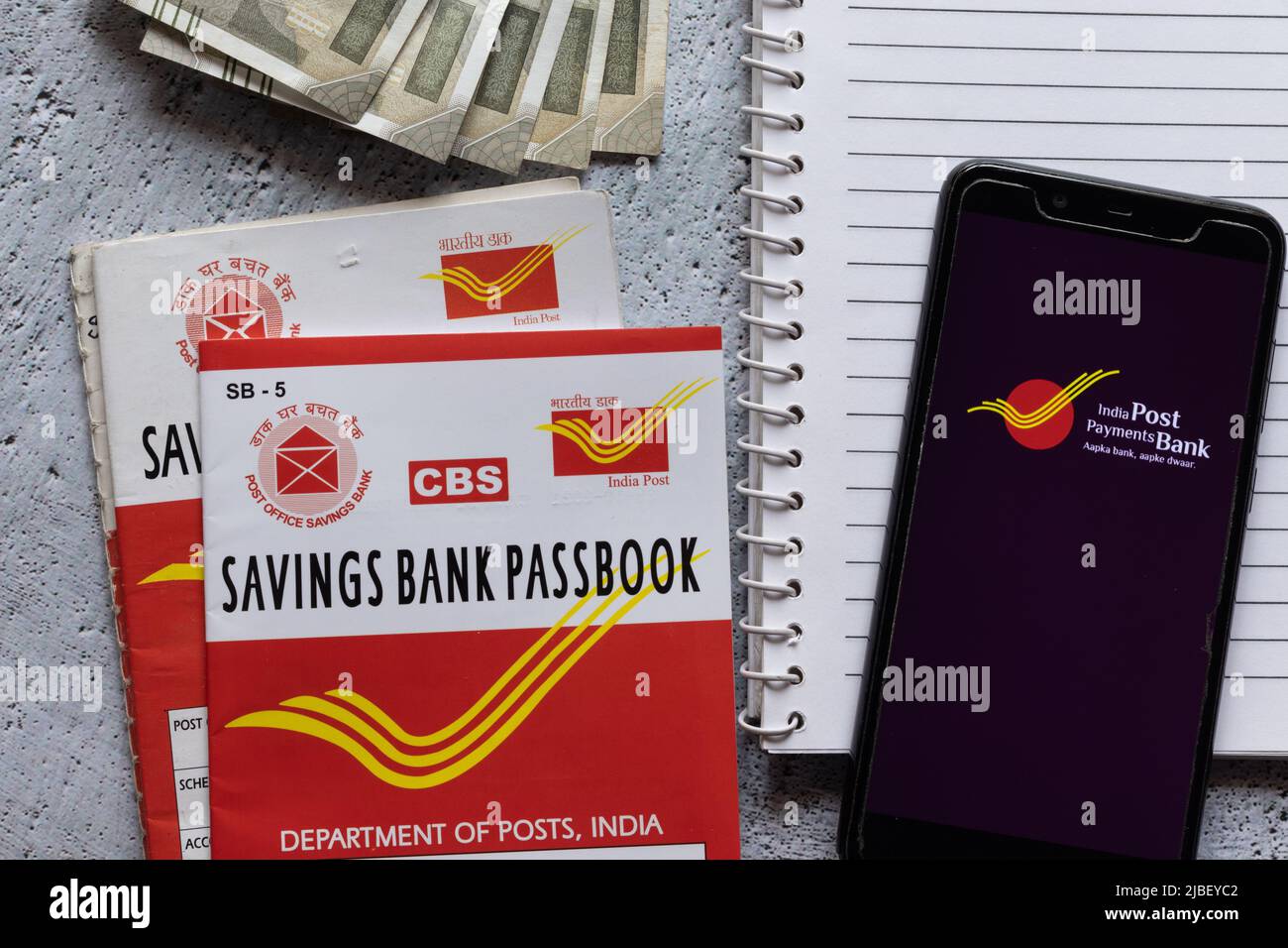 Birbhum, West Bengal, India - 25 April 2022: Top view of Indian post office savings books, currencies and smart phone with IPPB application Stock Photo
