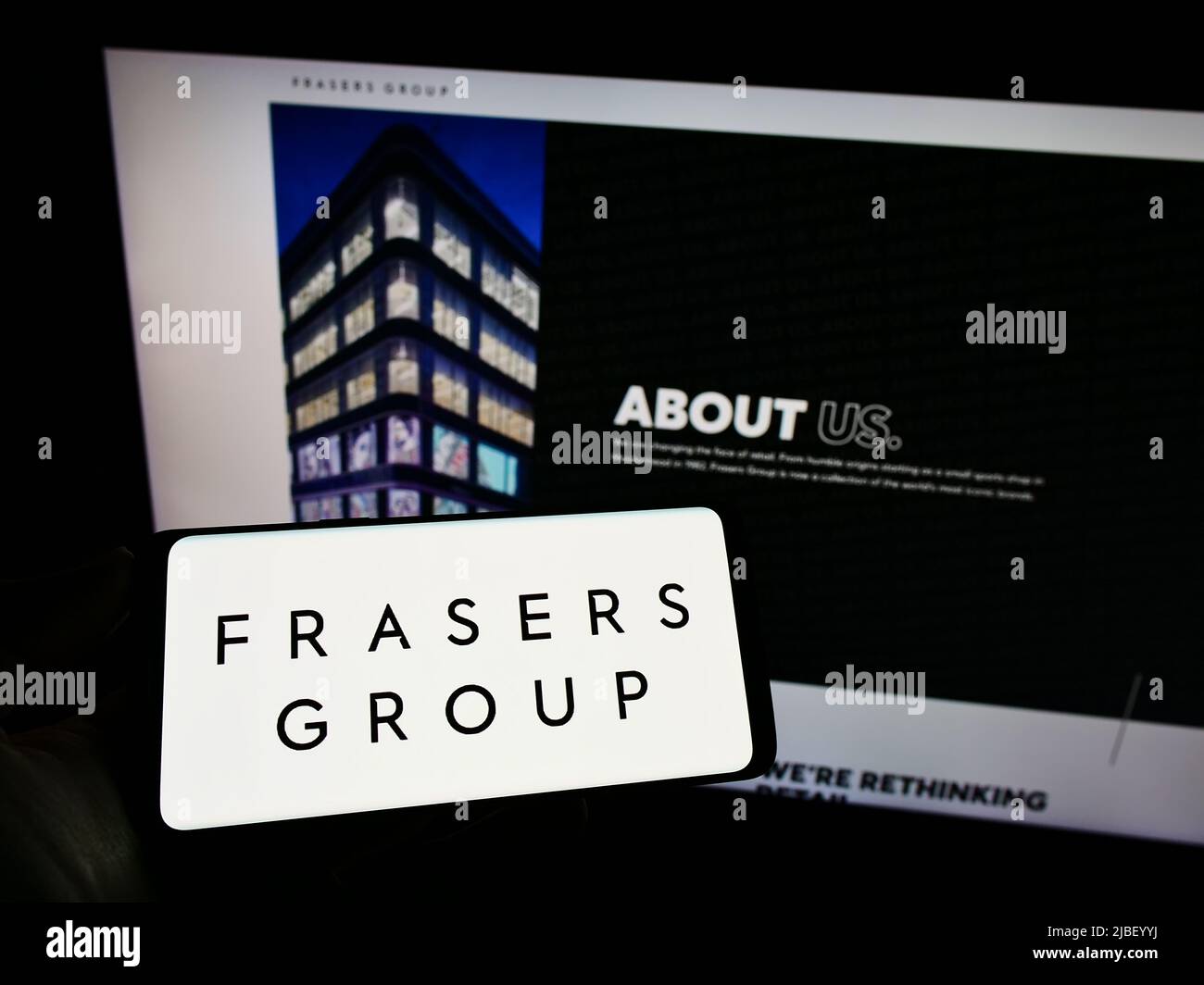 Person holding smartphone with logo of British retail company Frasers Group plc on screen in front of website. Focus on phone display. Stock Photo