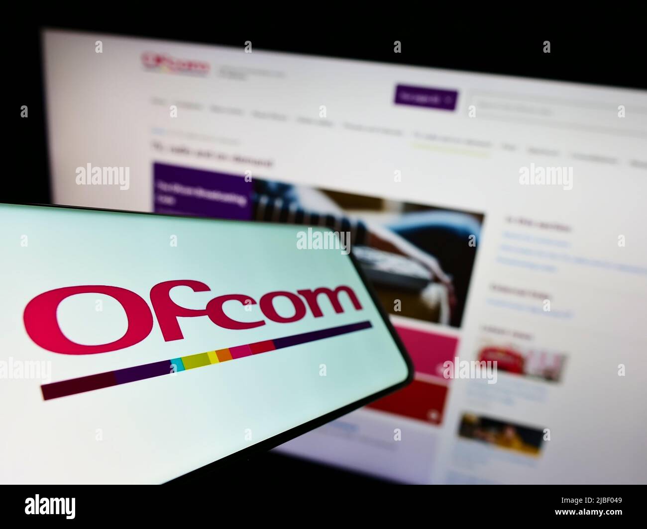 Smartphone with logo of British authority Office of Communications (Ofcom) on screen in front of website. Focus on center-left of phone display. Stock Photo