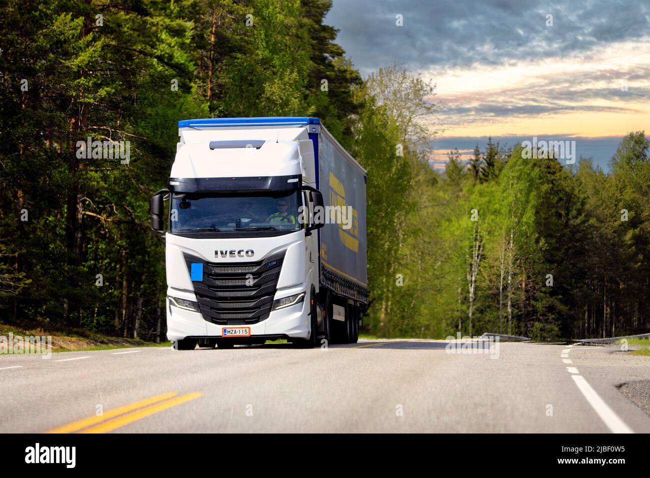 White gas-powered Iveco S-Way Natural Power, NP, truck in front of semi trailer on highway 52 in golden hour light. Raasepori, Finland. May 26, 2022. Stock Photo