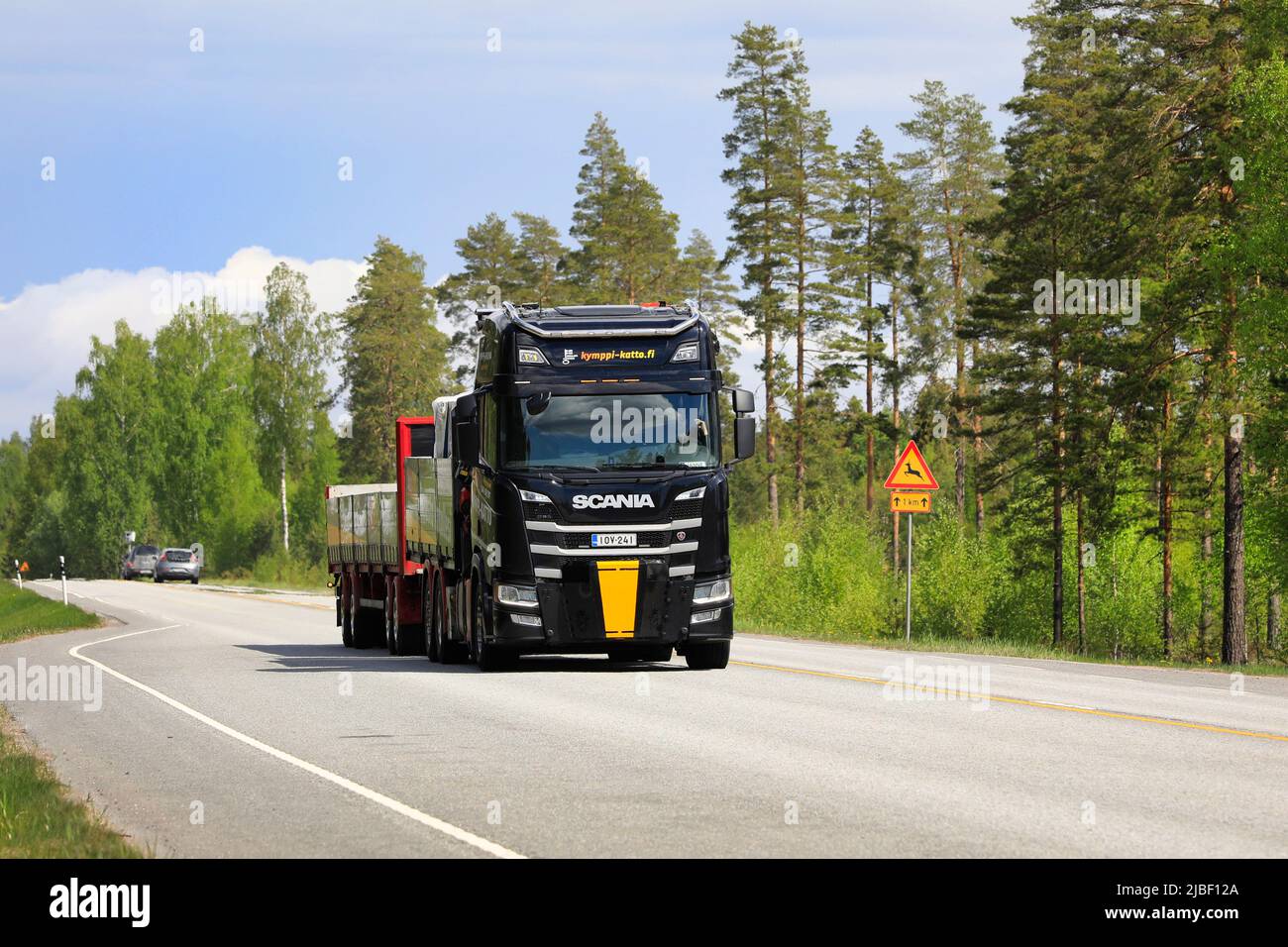 Black Scania truck and open trailer of Kymppi-Katto Oy transports load on road 25 on a sunny day. Raasepori, Finland. May 26, 2022. Stock Photo