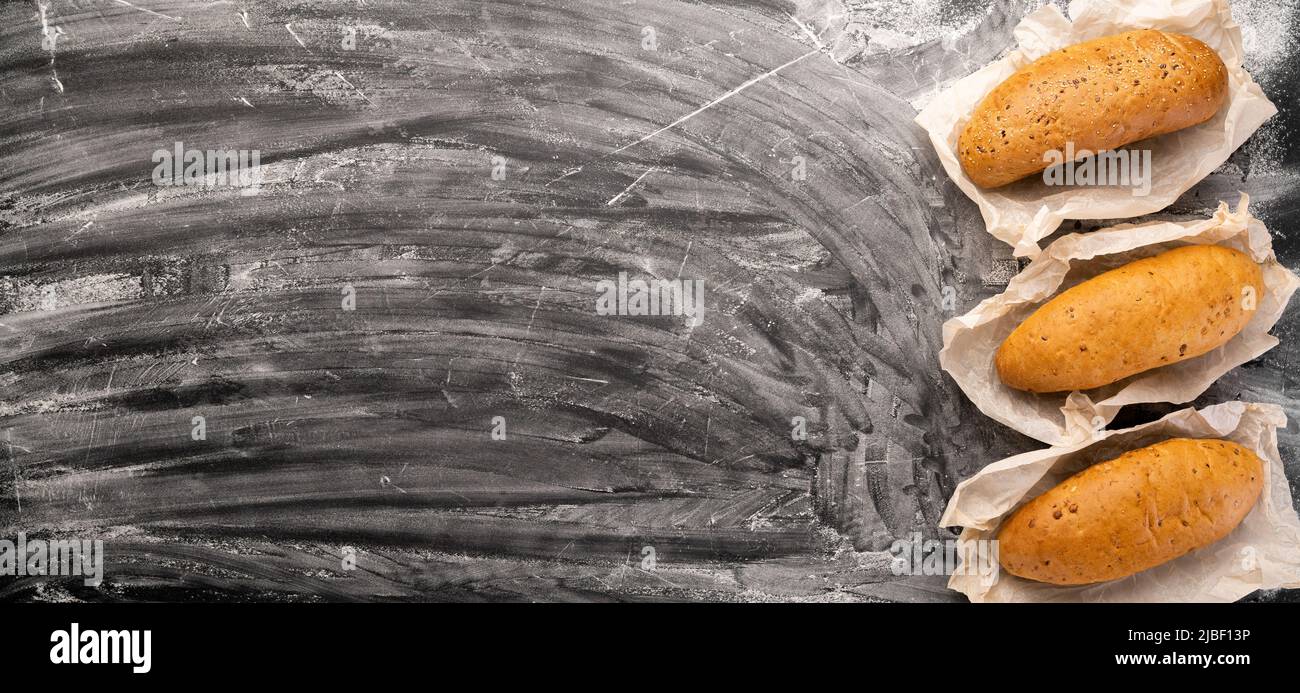 Assortment of delicious freshly baked breads on a black concrete background with flour top view copy space, banner Stock Photo