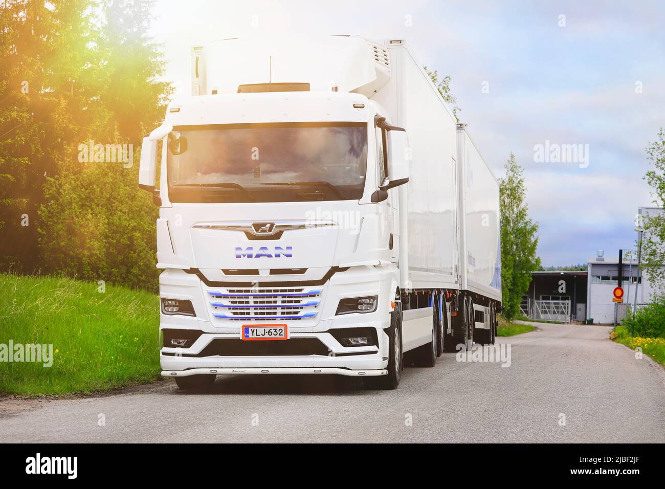 White, new MAN TGX 26.510 truck in front of refrigerated trailer parked on asphalt yard in golden hour light. Salo, Finland. May 29, 2022. Stock Photo