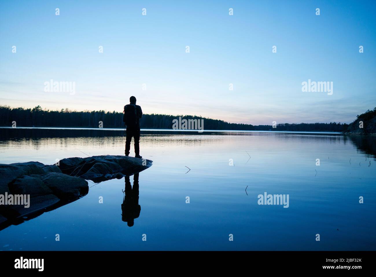 Silhouette of man by sea at sunset in Bjorno, Sweden Stock Photo