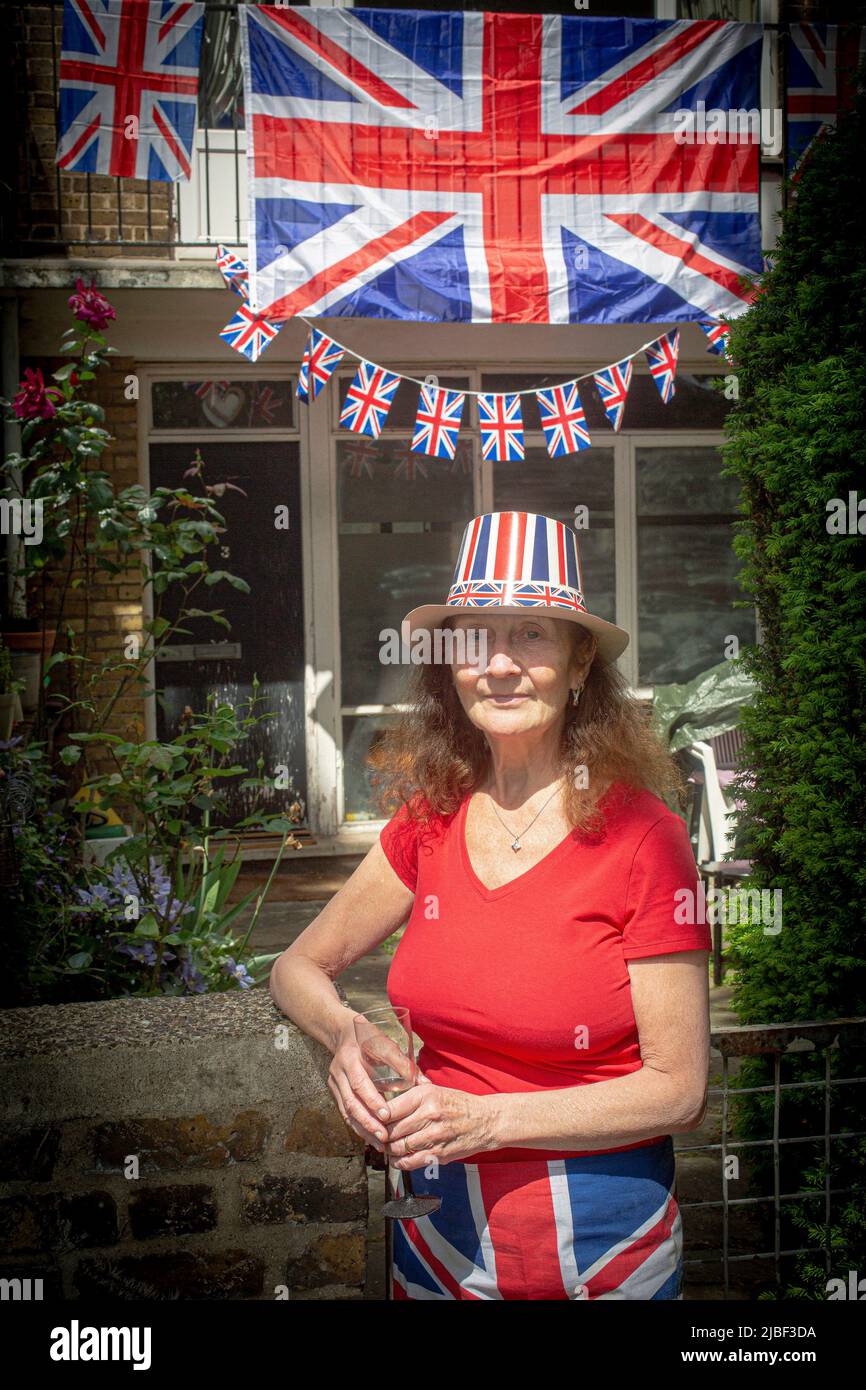 Woman in front of Union Jack flags and bunting outside a council house in London to celebrate 70 years of Her Majesty the Queen's reign. Stock Photo