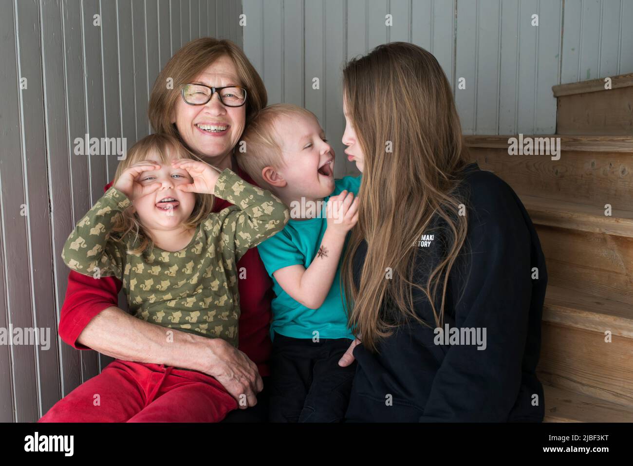 Woman sitting with her grandchildren on staircase Stock Photo