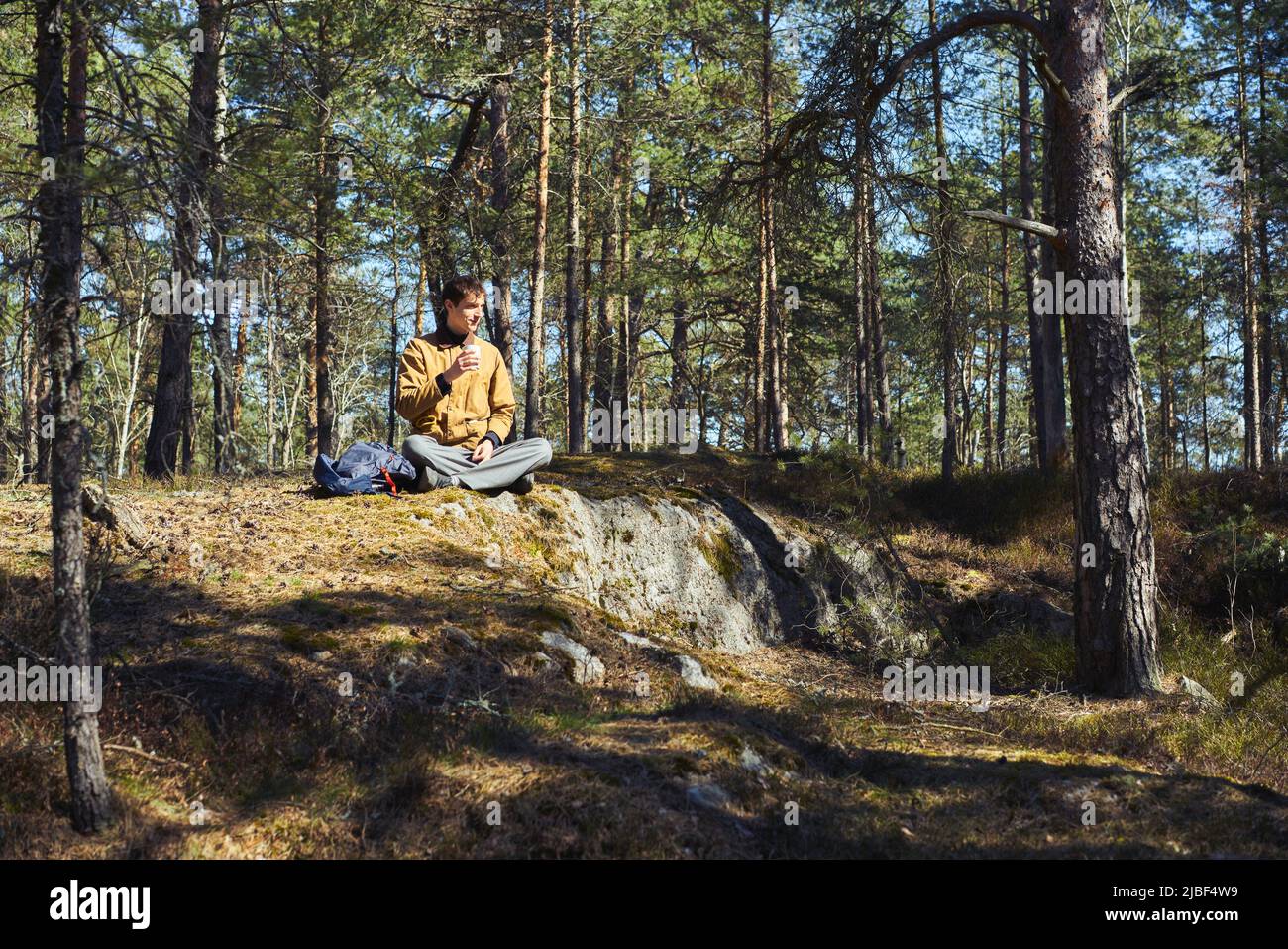 Man holding cup in forest in Djurgarden, Sweden Stock Photo