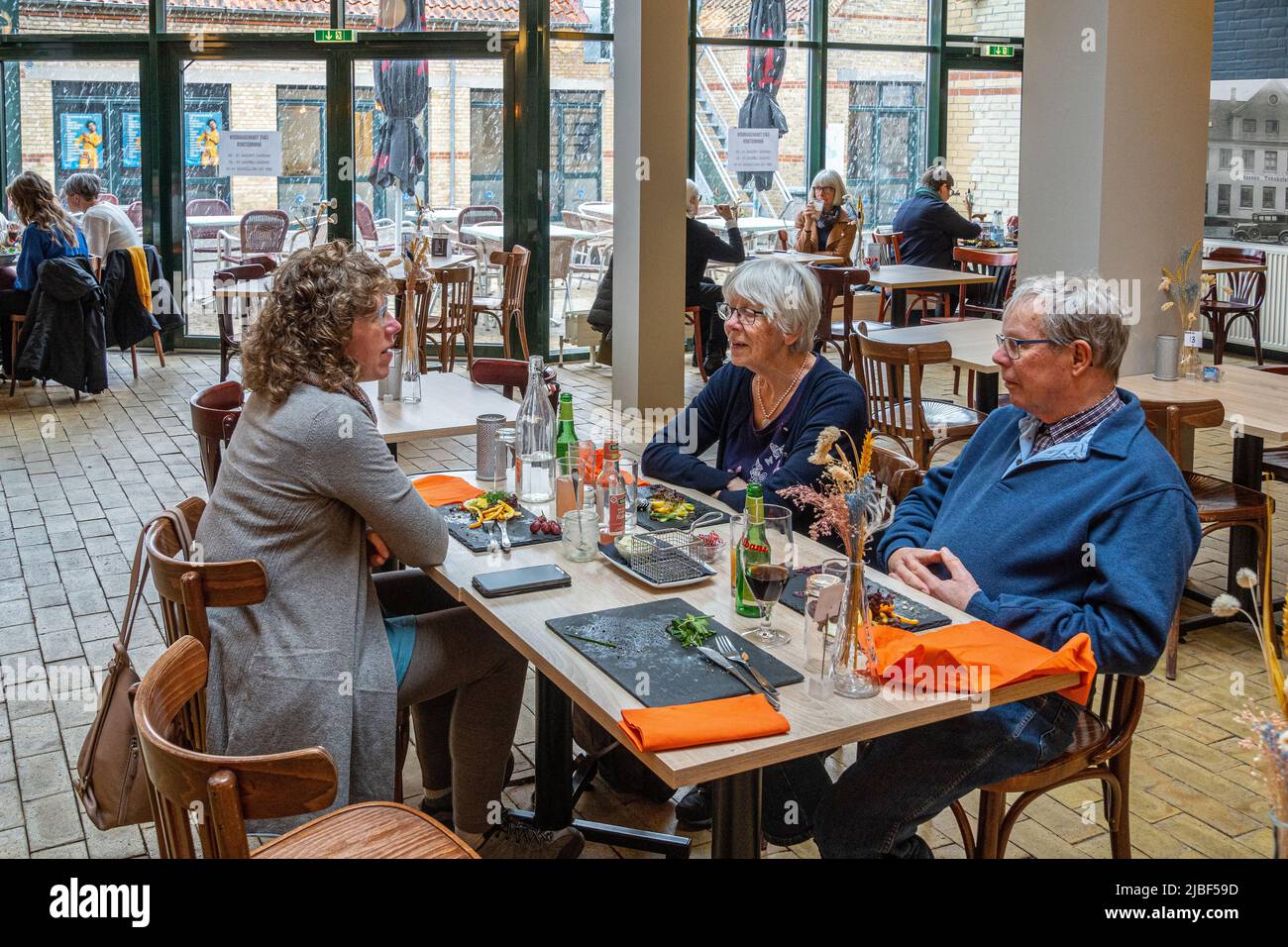 Elderly Danish couple sitting at a restaurant table with a girl chatting while waiting for the dishes. Assens, Denmark, Europe Stock Photo