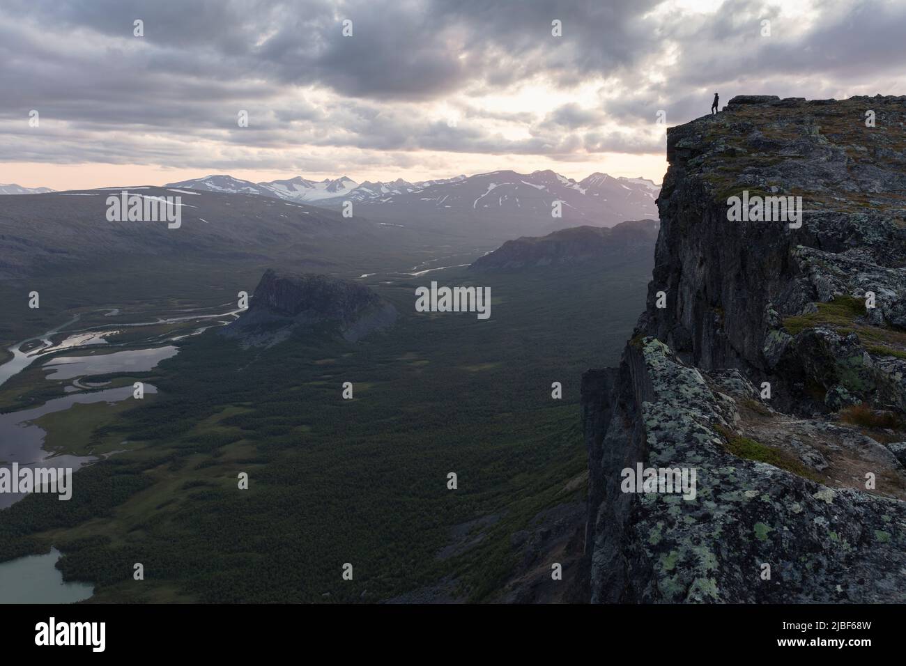Distant woman standing on cliff above Rapa Valley in Sarek National Park, Sweden Stock Photo