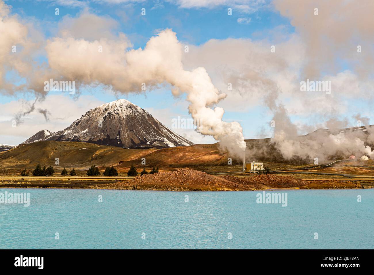 Behind a blue lake in the middle of Iceland lies the Myvatn Geothermal Area Stock Photo