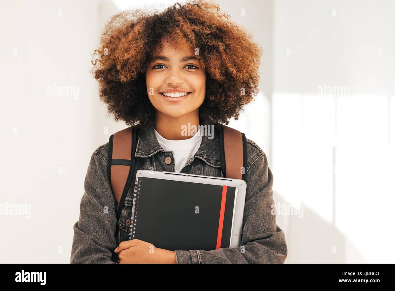 Close-up portrait of a female student holding book in front of her face ...