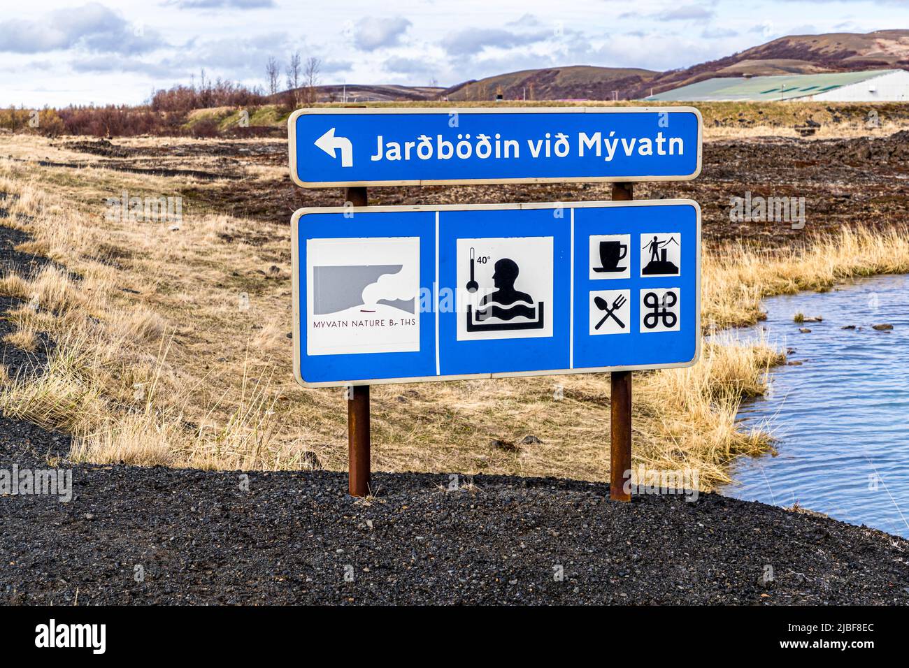 Behind a blue lake in the middle of Iceland lies the Myvatn Geothermal Area Stock Photo