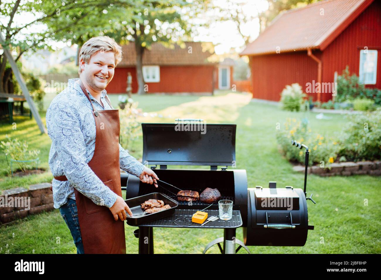 Young man cooking meat on barbecue Stock Photo Alamy