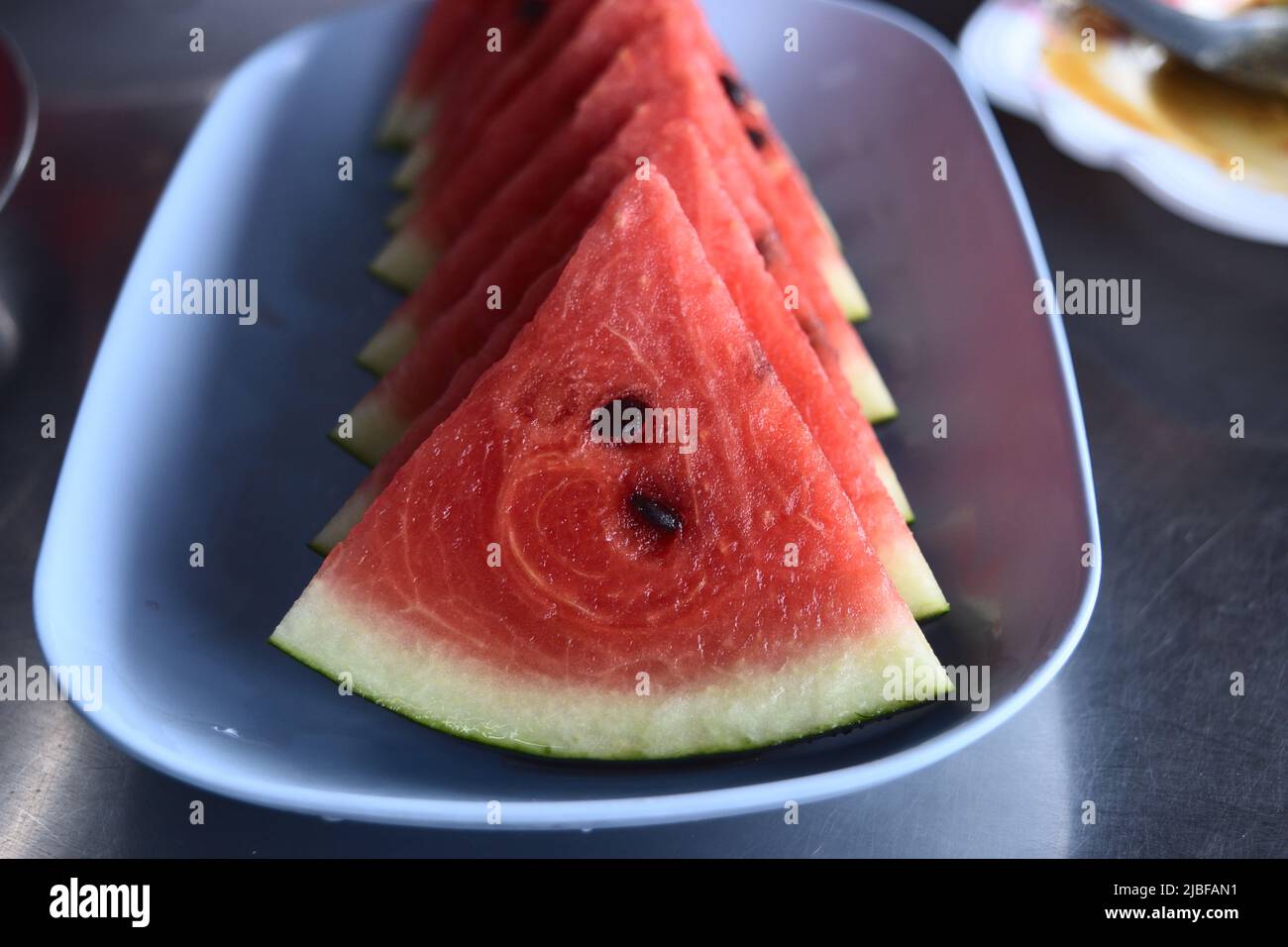 Sliced of watermelon in blue dish on table , Red juicy fruit flesh with green crust Stock Photo