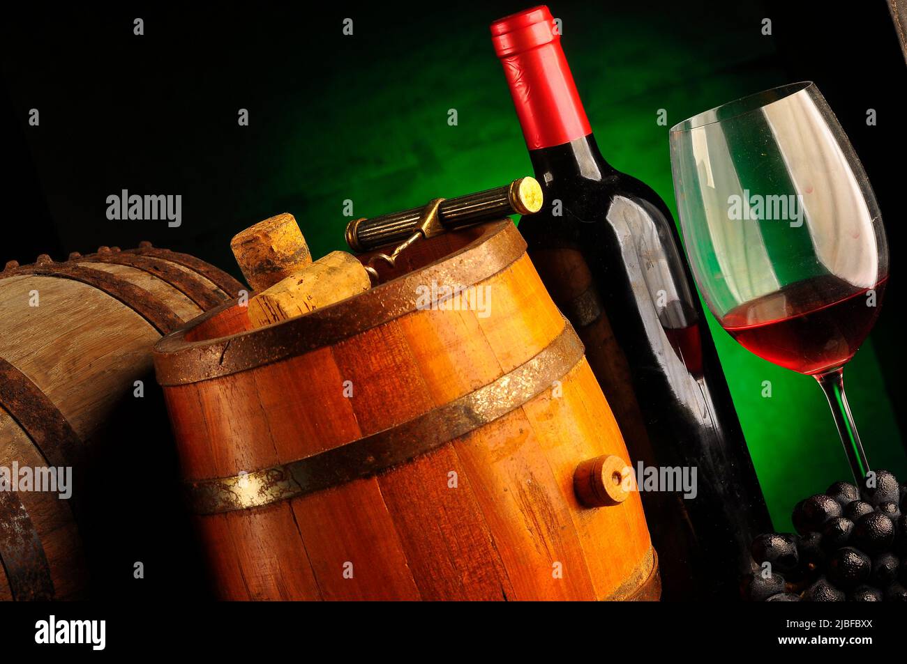 Glass and bottle of wine on the table, with a wooden barrel nearby