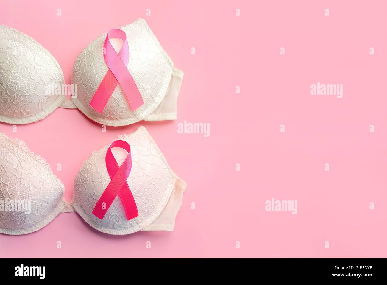 Breast cancer concept. Top view of women's bras and pink ribbon symbol breast cancer awareness over pink background Stock Photo
