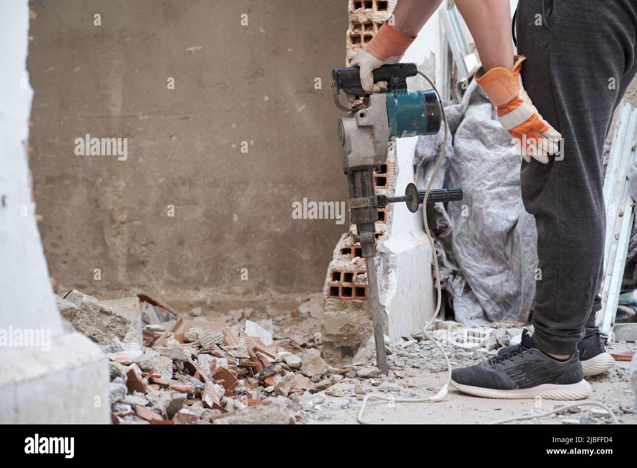 Unrecognizable man resting after using a jackhammer to drill into wall. Stock Photo