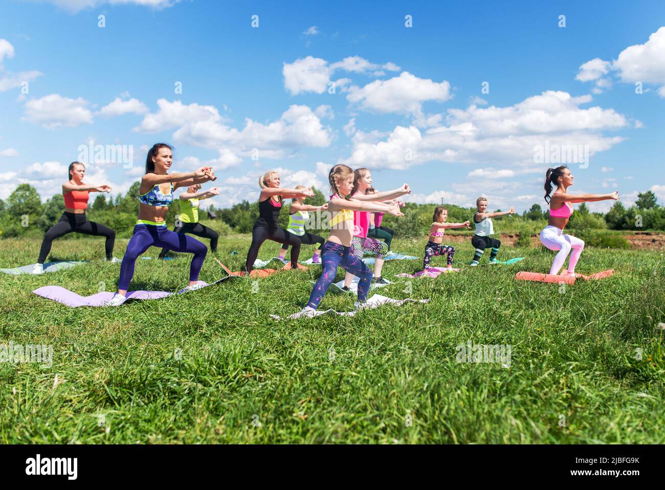 Group of women exercising and doing squats at boot camp Stock Photo