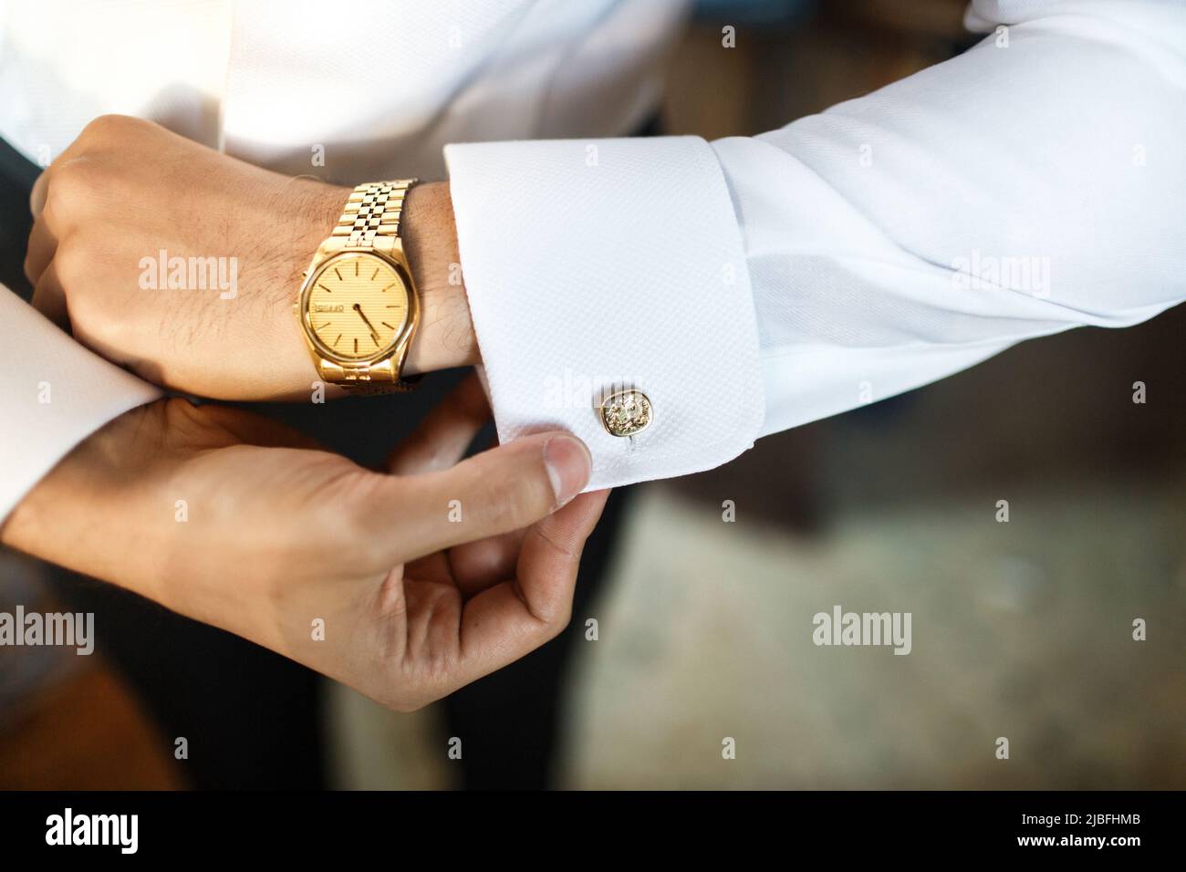 The groom fastens his cufflink at the wedding gathering. Stock Photo