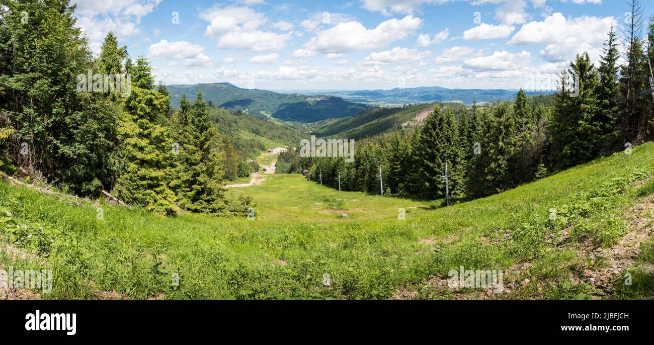 View of the Severka ski slope and a cableway in summer with the valley od Dolní Lomná and Beskydy (Beskid) mountain range in the background. Silesia, Stock Photo