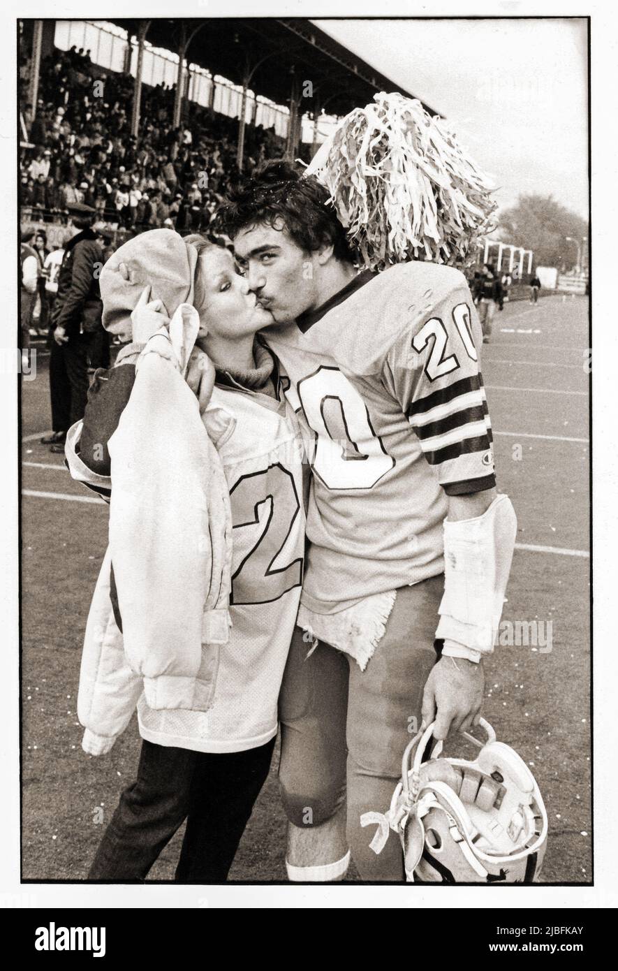After a football victory a Canarsie High School football player gets kiss from his girl friend who's wearing one of his jerseys. 1982 in Brooklyn, NYC. Stock Photo