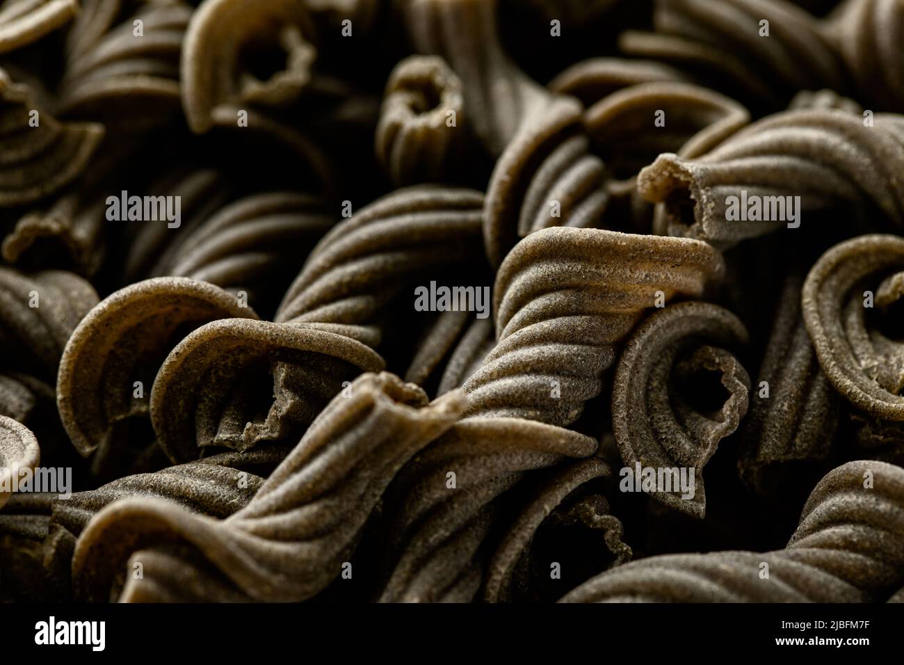 Close-up view of raw basil flavored sedanini pasta Stock Photo