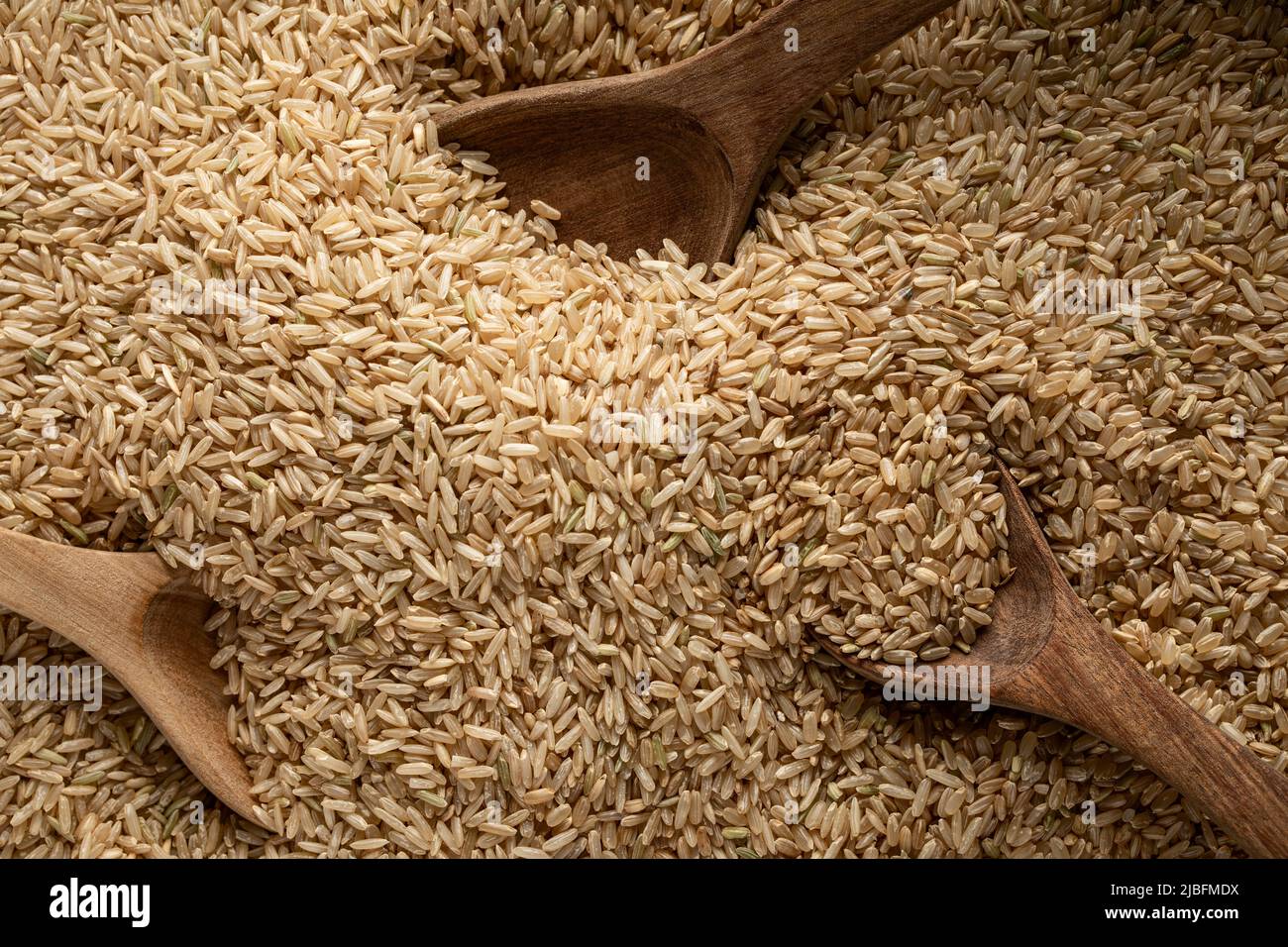 Top view of wooden spoon full of raw wholewheat rice Stock Photo
