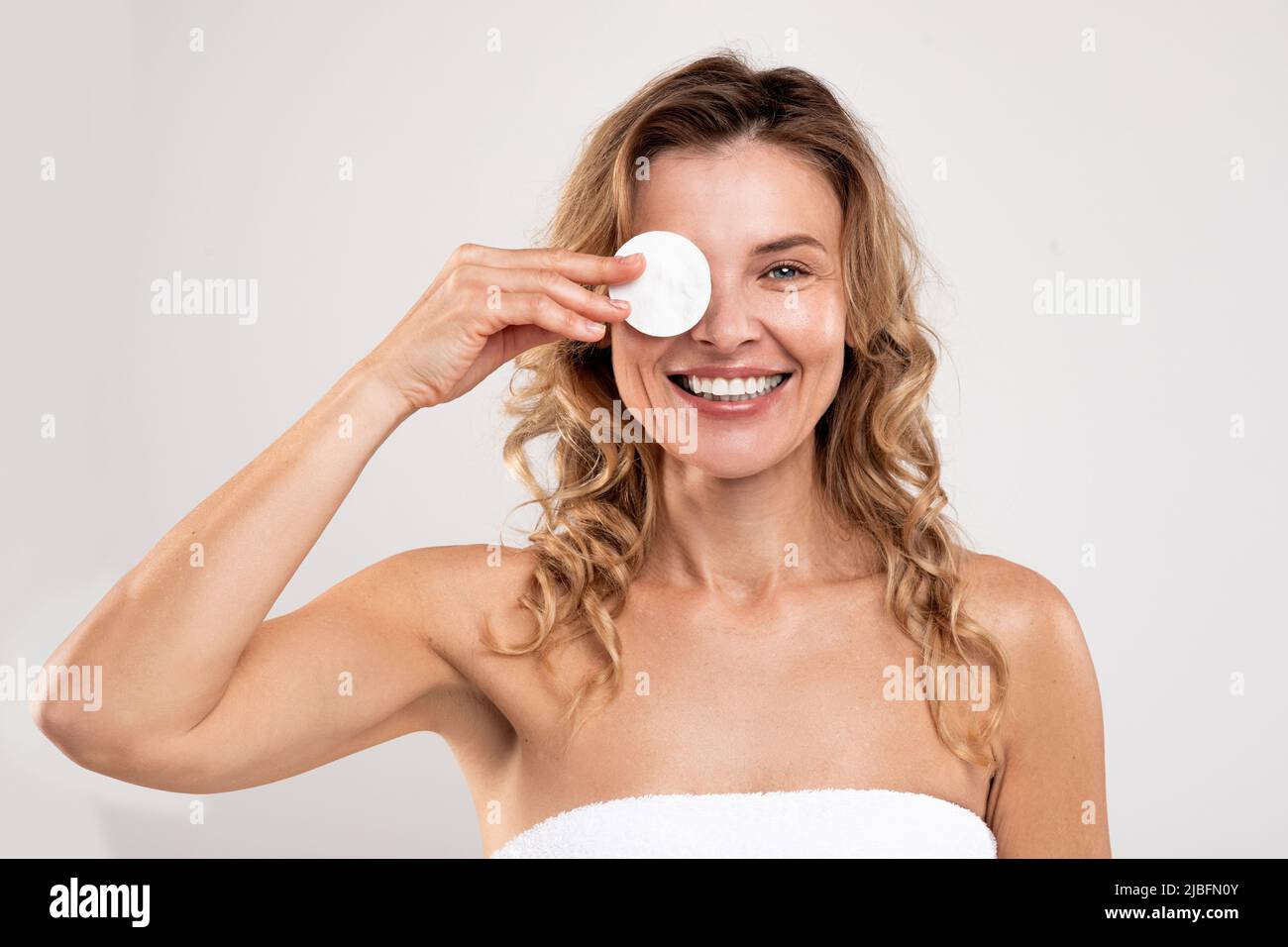 Facial Skincare. Cheerful Middle Aged Lady Covering Eye With Cotton Pad Stock Photo