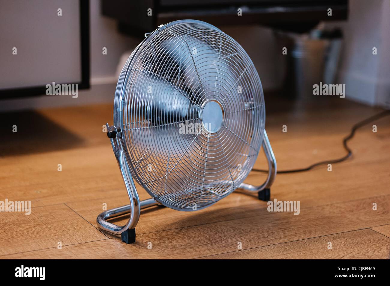 Metal fan blowing cold air placed on laminated wooden floor Stock Photo
