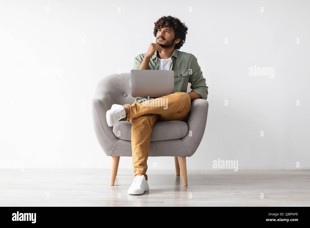 Thoughtful eastern man using computer, looking at copy space Stock Photo