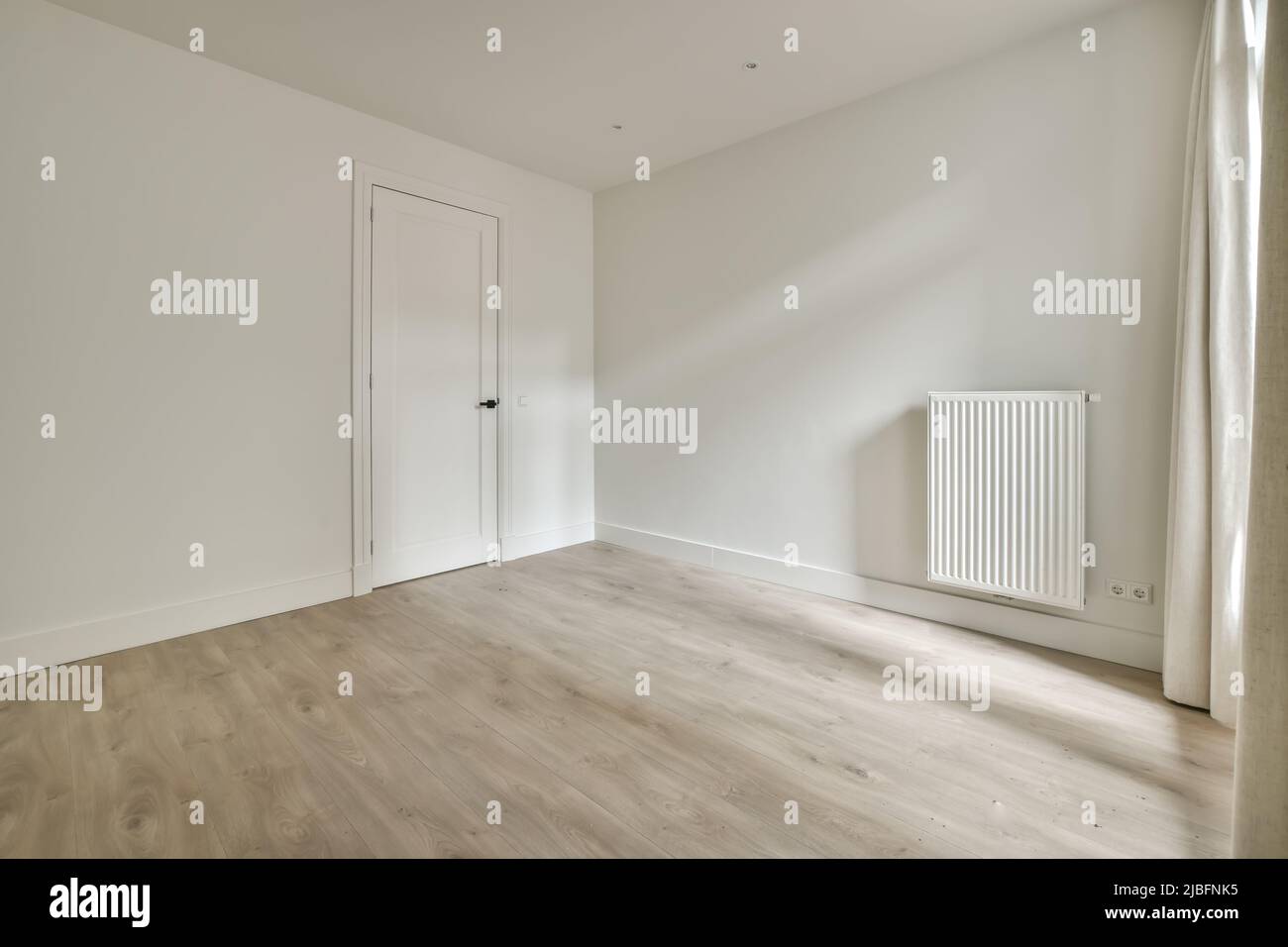 Interior of spacious empty refurbished living room with whitewash walls laminated floor with white door Stock Photo