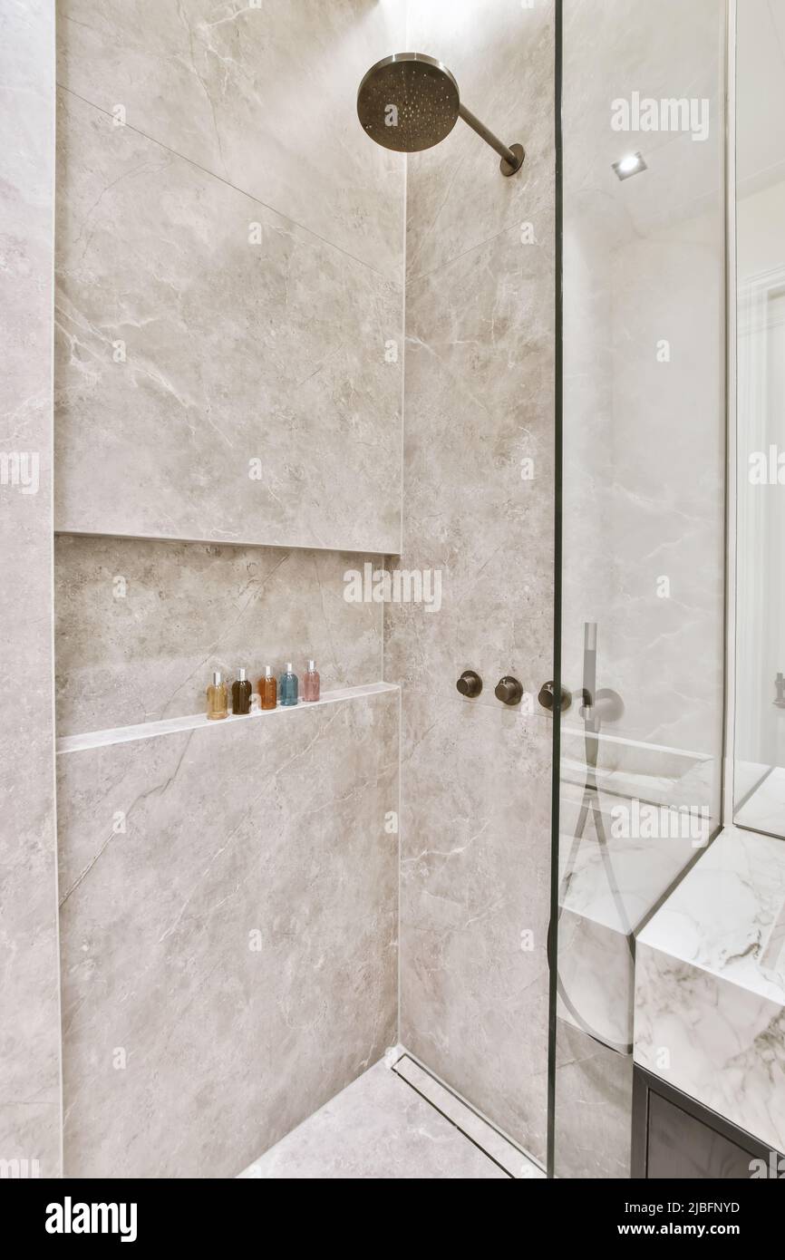 Shower cabin with modern appliances and gray marble tiled walls in