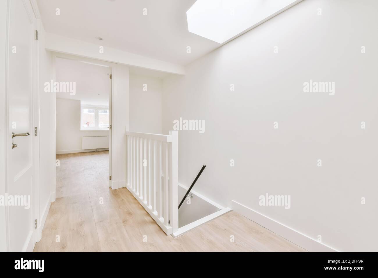 Staircase in spacious light hallway with white floor and walls on sunny day in modern house Stock Photo