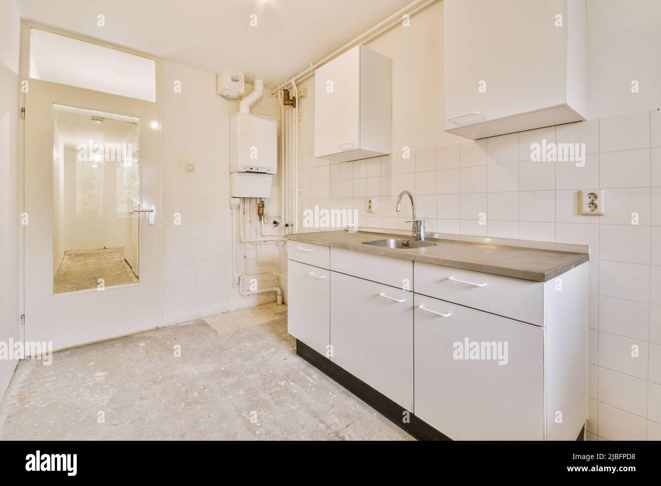 Old counter with white cabinets and tiled wall in light spacious kitchen in apartment under refurbish work Stock Photo