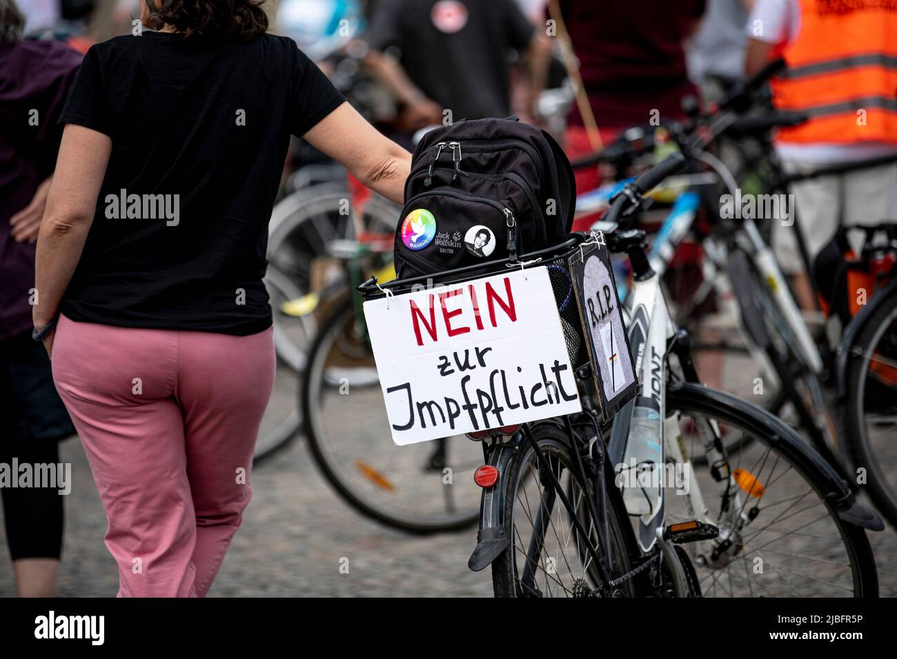 Berlin, Germany. 06th June, 2022. A participant in a bicycle demonstration  against compulsory Corona vaccination stands in front of the Brandenburg  Gate with a sign reading 