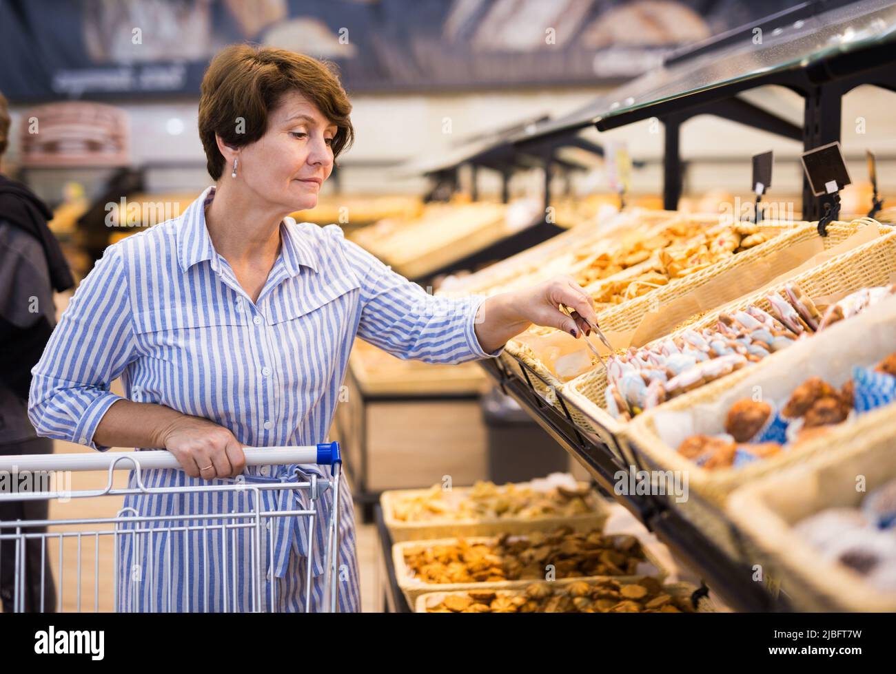 mature woman choosing bread and baking in grocery section of supermarket Stock Photo