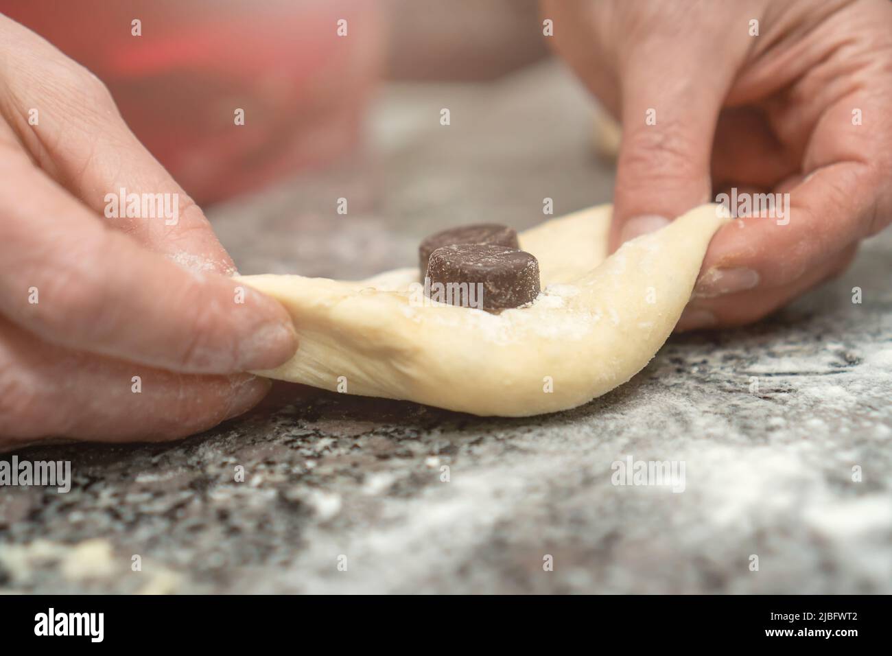 Closeup of female pastry chef's hands laying chocolate in yeast dough